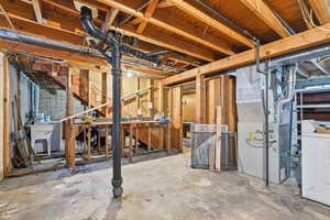 Unfinished basement with heating unit, washer / dryer, and gas water heater