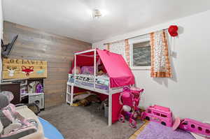 Carpeted bedroom featuring wood walls