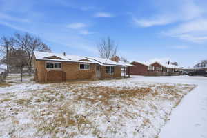Snow covered property with a chimney and brick siding