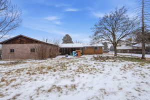 Snow covered back of property with a patio area