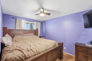 Bedroom featuring light wood-style floors, a textured ceiling, and ceiling fan
