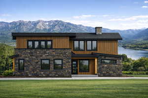 View of front of house featuring stone siding, a mountain view, a front yard, and a chimney