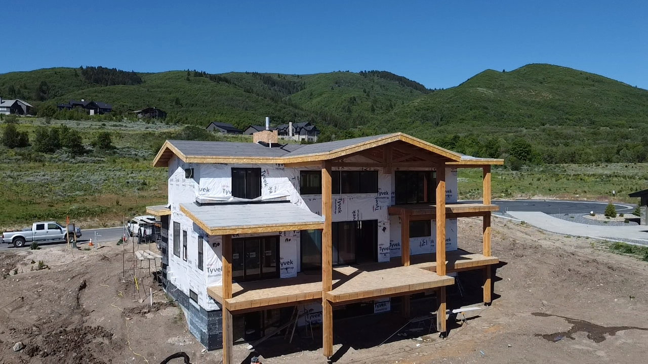 Multi-level residence under construction with a dark shingle roof and multiple wood-framed decks