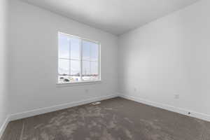 Empty room featuring baseboards and dark colored carpet