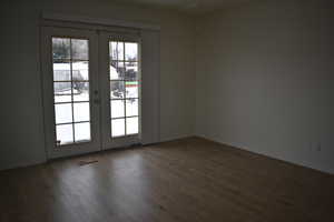 Unfurnished room featuring french doors and dark wood-style floors