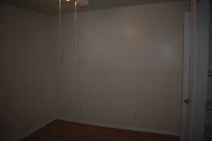 Unfurnished room with dark wood-type flooring and a ceiling fan