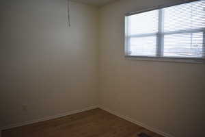 Empty room featuring dark wood-type flooring and baseboards