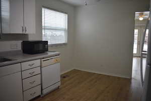 Kitchen featuring white cabinetry, dishwasher, black microwave, light wood-type flooring, and a ceiling fan