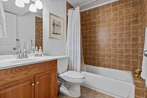 Bathroom with vanity, shower / bath combo with shower curtain, and light tile patterned floors