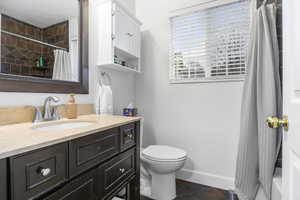 Full bathroom with tiled shower, vanity, and dark tile patterned floors