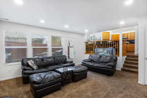 Living area with dark colored carpet and recessed lighting