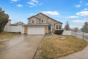 Traditional-style house featuring a gate, stucco siding, a garage, concrete driveway, and brick siding