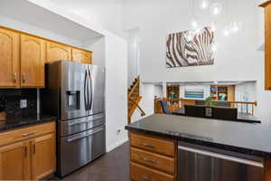 Kitchen with stainless steel appliances, dark stone countertops, dark tile patterned floors, and wood finish cabinetry