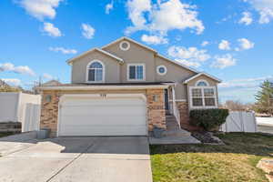 Traditional-style home with brick siding, concrete driveway, stucco siding, and a garage