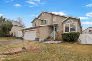 Traditional home with brick siding, stucco siding, driveway, and a gate