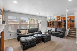 Living room featuring light colored carpet, a fireplace, recessed lighting, and a textured ceiling