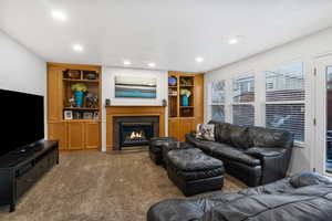 Carpeted living room featuring built in shelves, a fireplace, and recessed lighting