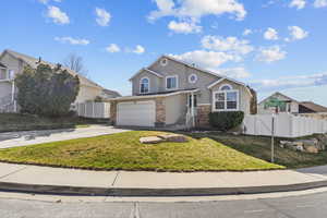 View of front of house with stucco siding, concrete driveway, a garage, brick siding, and a gate