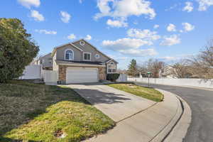 Traditional home featuring driveway, an attached garage, stucco siding, brick siding, and a gate
