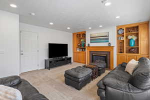 Carpeted living room featuring built in shelves, recessed lighting, and a tiled fireplace