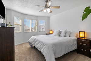 Bedroom with dark carpet, a ceiling fan, and a textured ceiling
