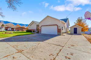 View of front of house featuring driveway, a mountain view, a front lawn, an attached garage, and brick siding