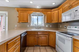 Kitchen featuring white appliances, light countertops, wood finish cabinets, recessed lighting, and light tile patterned floors