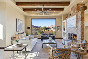 Living area with a fireplace, a ceiling fan, and beam ceiling