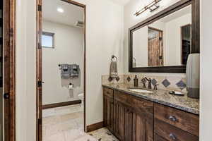 Full bathroom with vanity, stone tile floors, and recessed lighting