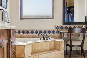 Full bathroom with a bath, a spacious closet, healthy amount of natural light, and vanity