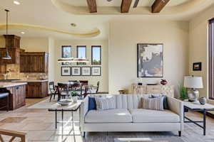Living area with recessed lighting, a tray ceiling, beam ceiling, and stone tile flooring