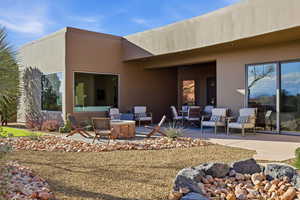 Back of house with a patio area, stucco siding, and an outdoor living space with a fire pit