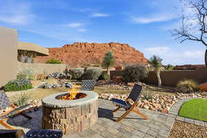 Fenced backyard with an outdoor fire pit, a patio area, and a mountain view