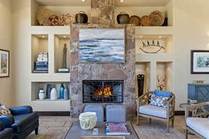 Living room featuring built in features and a stone fireplace
