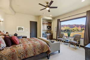 Bedroom with a mountain view, light colored carpet, recessed lighting, bar area, and ceiling fan