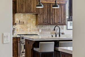 Kitchen with stainless steel stove, tasteful backsplash, and light stone counters