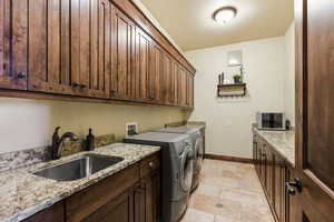 Laundry room with stone tile flooring, washer and clothes dryer, and cabinet space