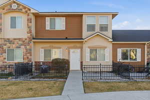 View of front facade featuring stone siding, stucco siding, and a fenced front yard