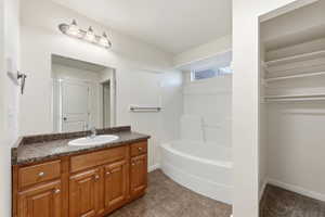 Master bath featuring vanity,  shower combination, and dark tile patterned flooring