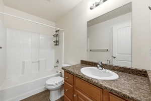 Full bath with bathing tub / shower combination, vanity, a textured ceiling, and dark tile patterned flooring