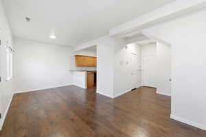 Unfurnished living room with dark wood-type flooring and baseboards