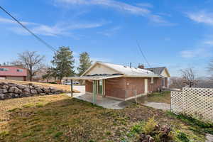Back of property featuring brick siding, a patio area, a chimney, and a lawn