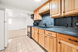 Kitchen featuring black appliances, light colored carpet, dark countertops, light tile patterned floors, and recessed lighting
