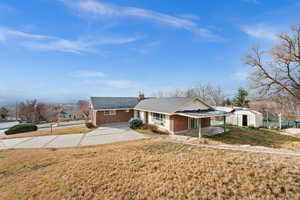 Ranch-style house featuring brick siding, a front lawn, driveway, a chimney, and an outdoor structure
