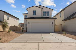 View of front of house with an attached garage, concrete driveway, and stucco siding