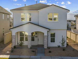 View of front facade featuring stucco siding, a porch, and stone siding