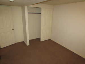 Unfurnished bedroom with dark colored carpet and a closet