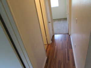 Hall with dark wood finished floors and dark colored carpet