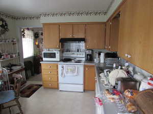 Kitchen with white appliances, light flooring, decorative backsplash, and wood finish cabinets