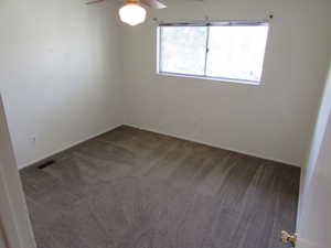 Unfurnished room featuring ceiling fan and dark carpet